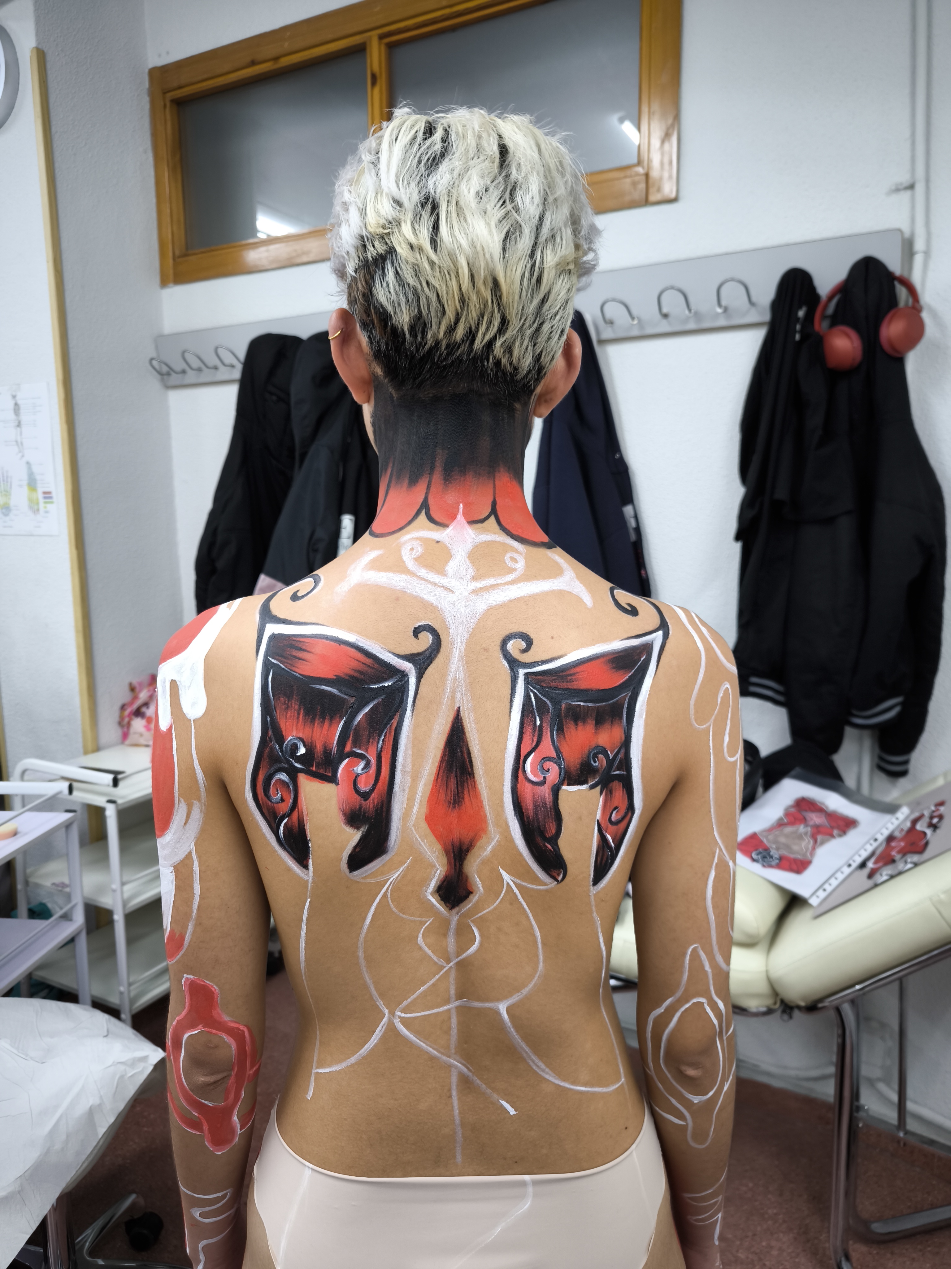 Vista trasera del body painting con diseño de mariposa en la espalda