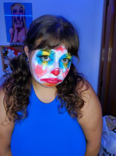 Retrato frontal con pelo rizado suelto: base blanca, nariz roja, labios rojos y lágrimas azules pintadas